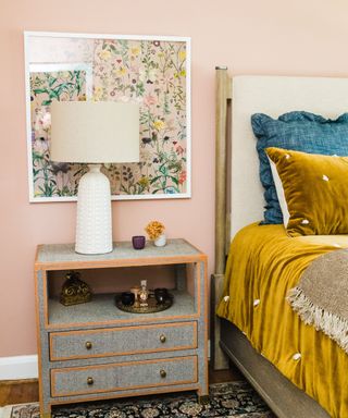 bedroom with putty pink walls and mustard yellow bedding and vintage rug