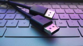 A pair of DisplayPort cable connectors laid across a laptop keyboard.