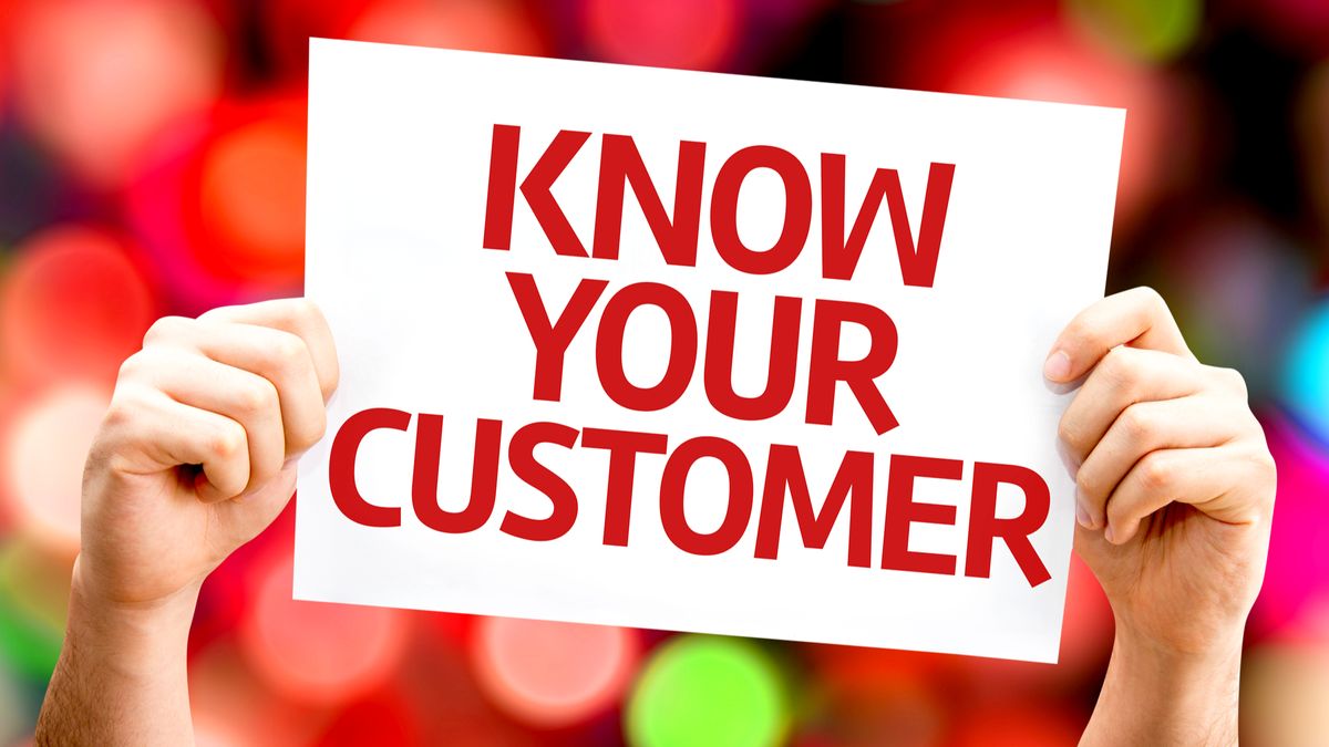 Hands holding up a sign saying &amp;#039;know your customer&amp;#039; in red letters