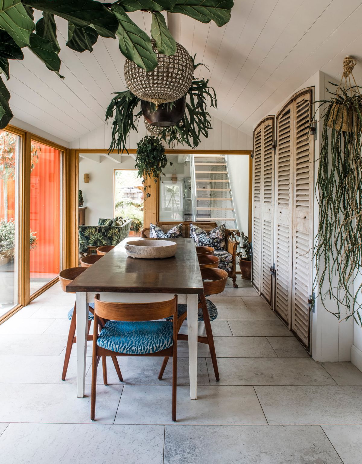 A garden room with a dining table, a glass chandelier and houseplants