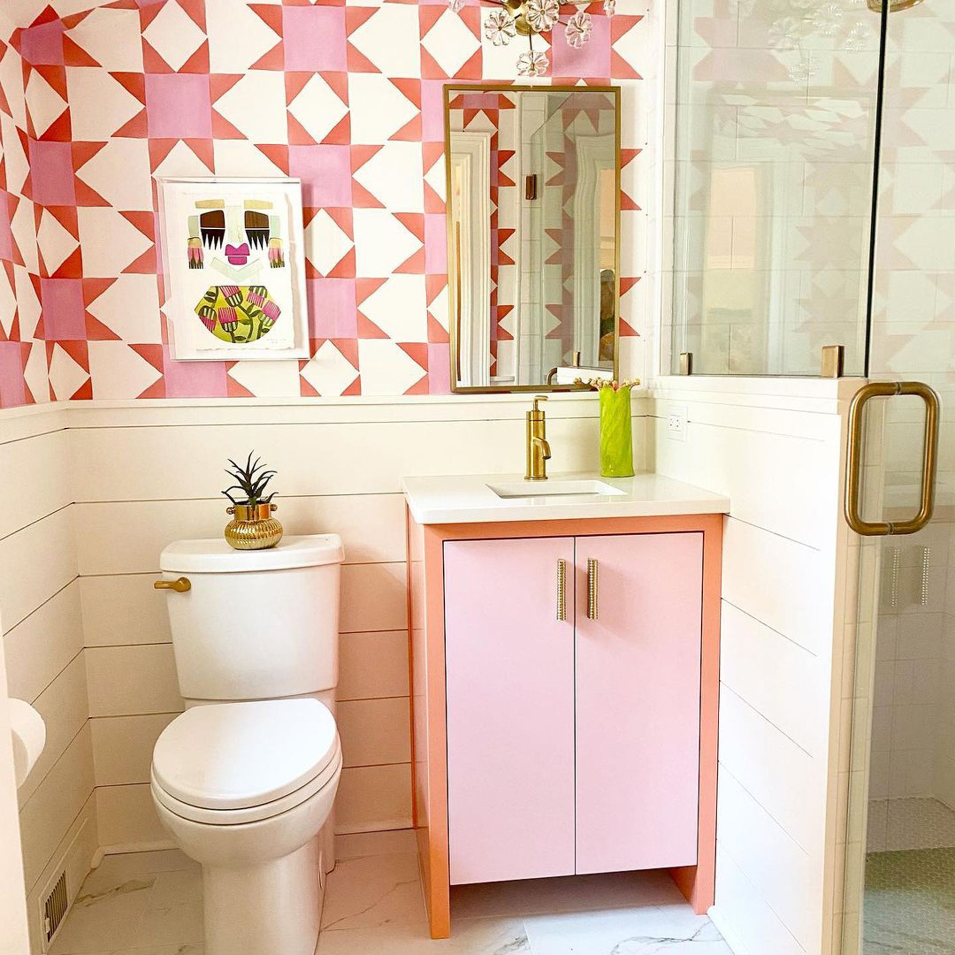 Kamar mandi kecil yang menarik dengan meja rias dua warna yang lucu dan wallpaper bermotif pink grafis yang serasi