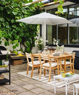 Outdoor patio with parasol, rug, wood table and chairs, outdoor kitchen