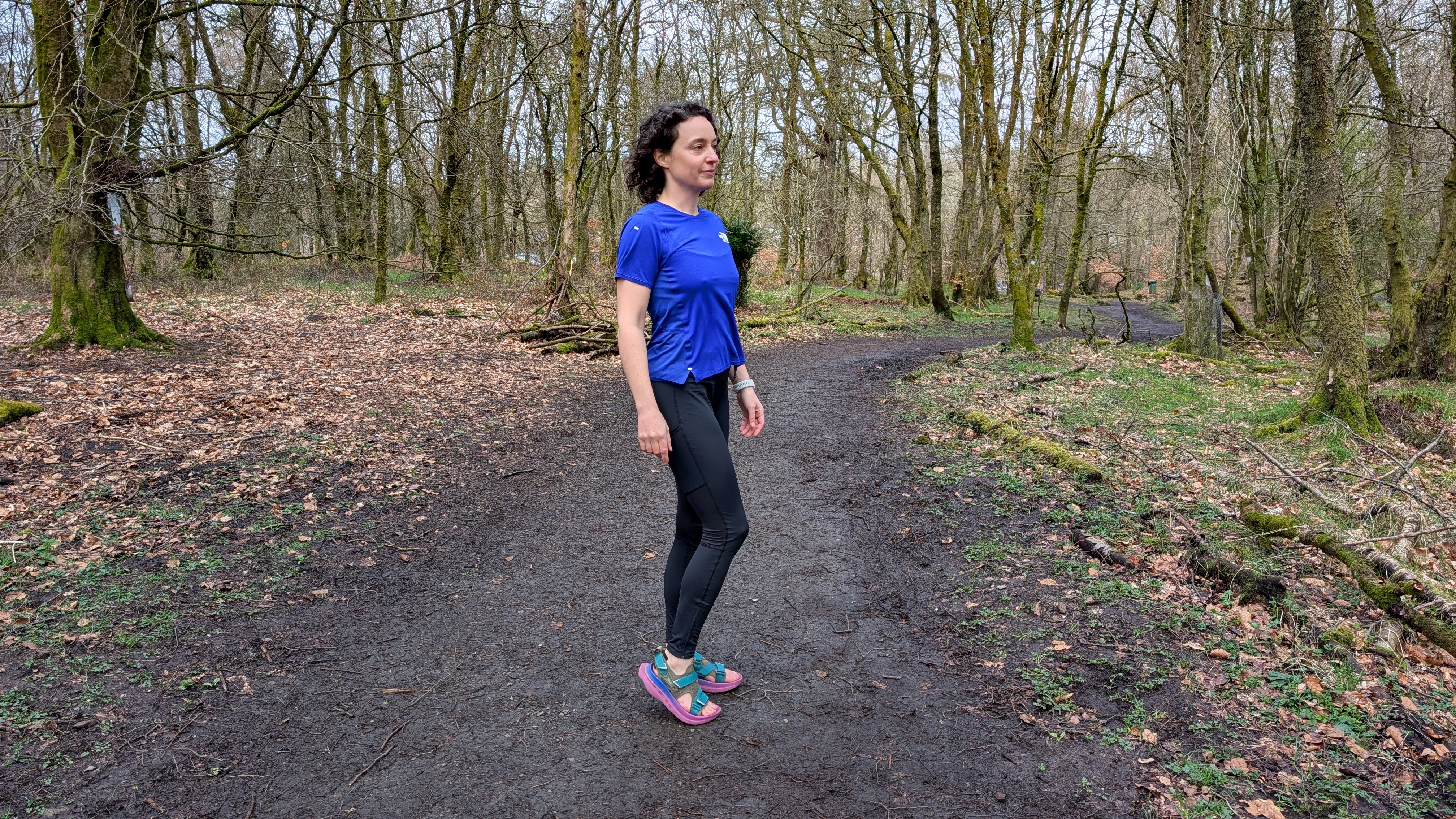 A runner on the trail wearing Teva Aventrail running sandals and a blue running top