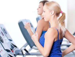 Two women run on treadmills.