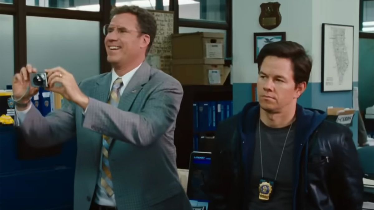 Will Ferrell in glasses and holding a camera while Mark Wahlberg looks on.