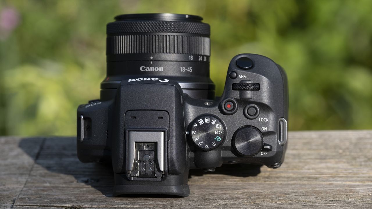 The top of the Canon EOS R10 camera sitting on a wooden bench