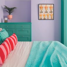 Bedroom with bright green chest of drawers and lilac wall.
