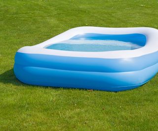 A blue inflatable kiddie pool filled with water on a lawn