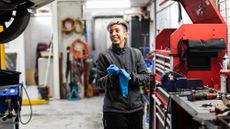 A mechanic in a garage cleaning her hands with a blue cloth