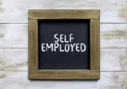 the words self employed written on a framed chalkboard 