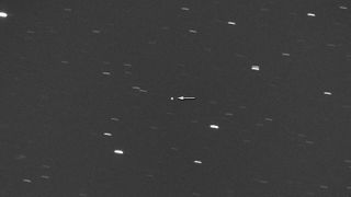 An image showing the potentially hazardous asteroid 2008 DG5 indicated by a white arrow against a dark sky dotted with star lines.