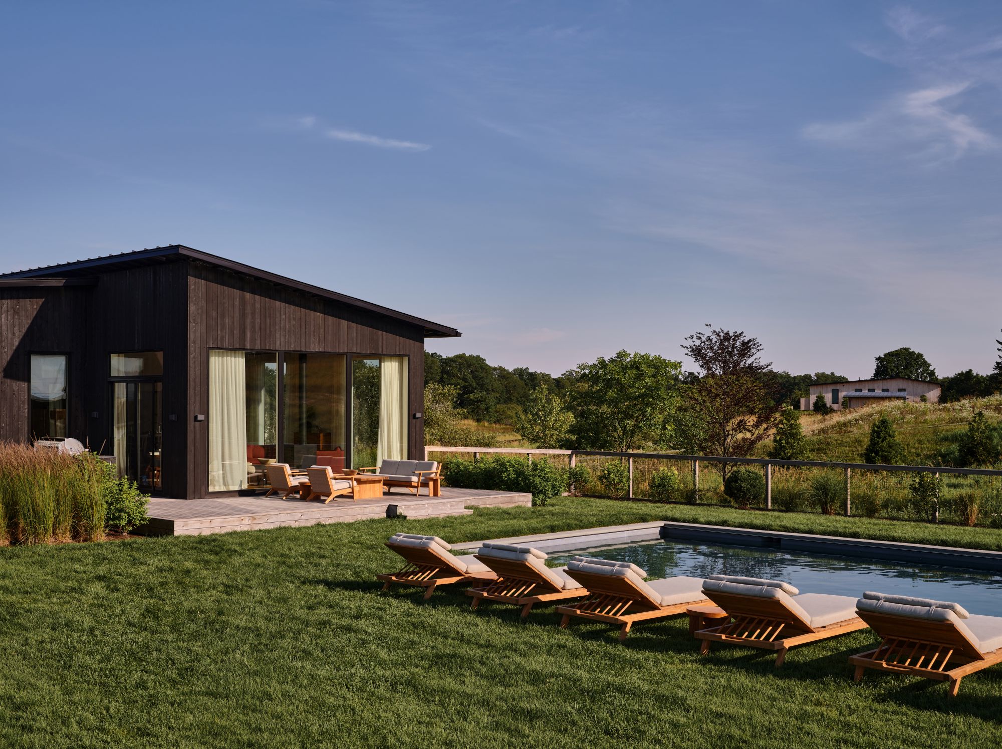 backyard with five lounge chairs in front of an in-ground pool