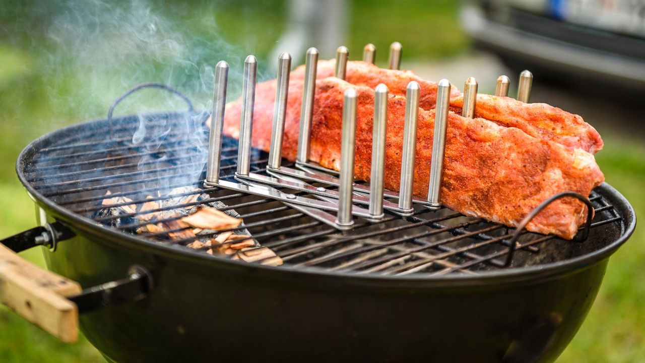 An image demonstrating &#039;can a regular grill be a smoker&#039;, a rack of ribs smoking on a Weber Kettle grill