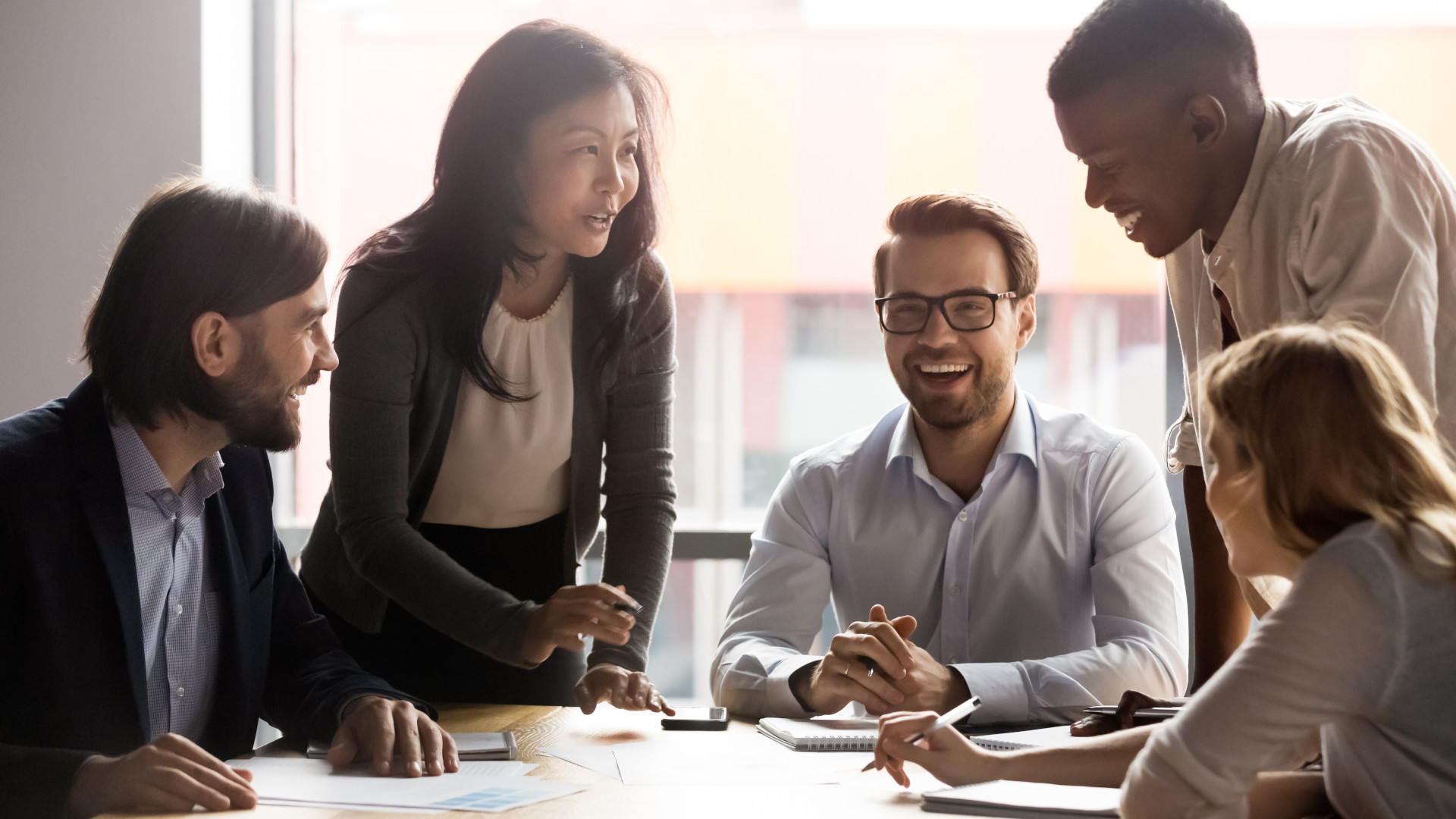 Four business professionals smiling around a table