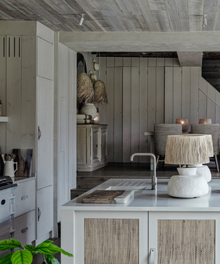 modern kitchen in cottage in muted colours with pale woode ceiling and ceramic light with raffia pendant
