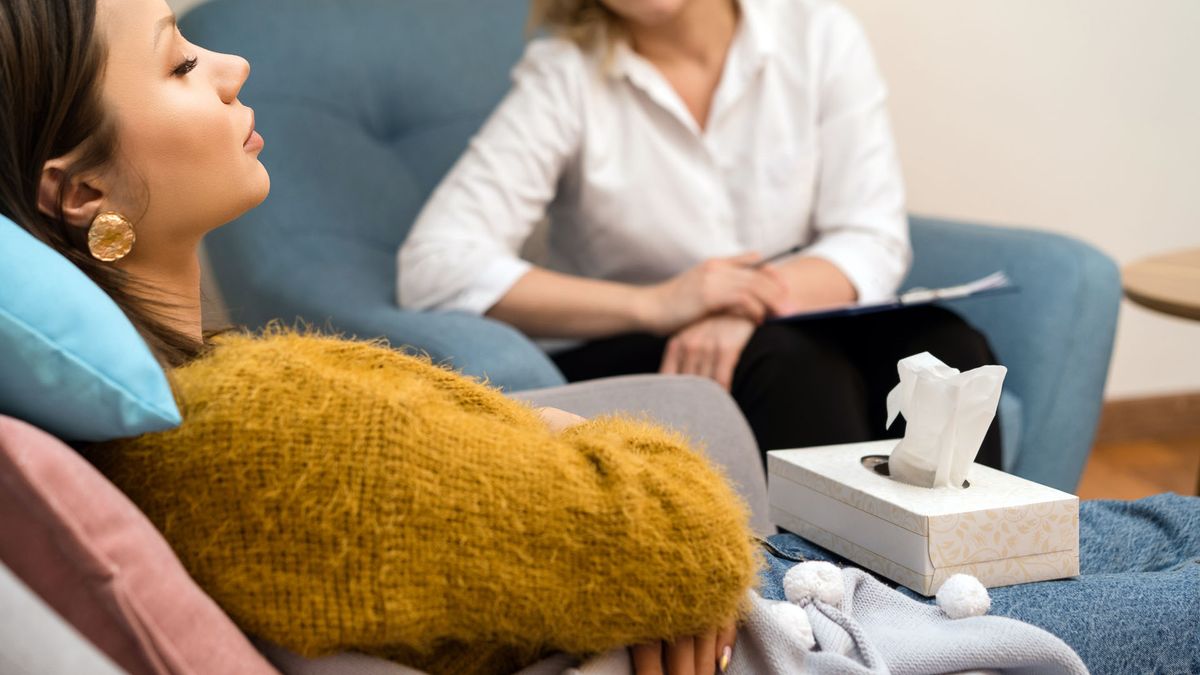 Positive blonde middle-aged woman psychologist talking to girl patient. 