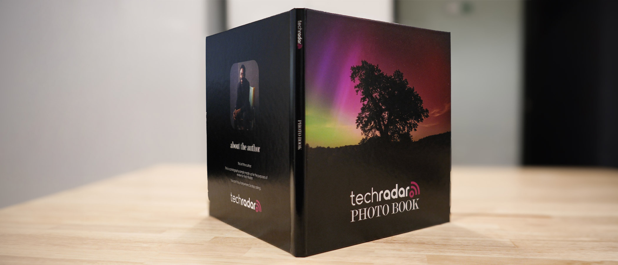 The Printique photo book propped open so you can see the front and rear covers simultaneously; the front image shows an aurora and the words &#039;TechRadar Photo Book&#039;.
