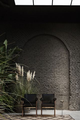 Two black chairs against a painted brick wall
