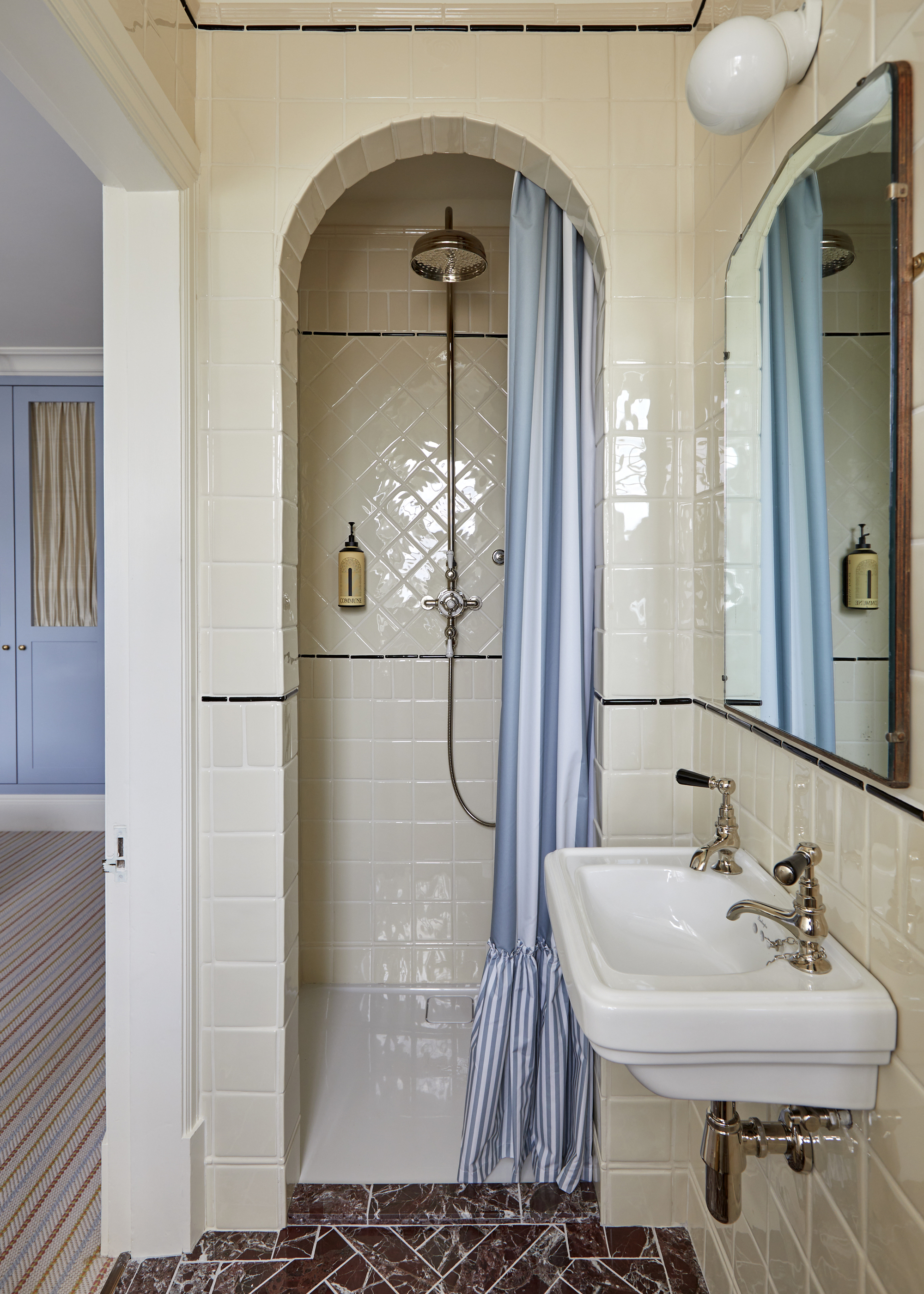A bathroom with traditional tiles and an arched doorway leading to a walk-in shower