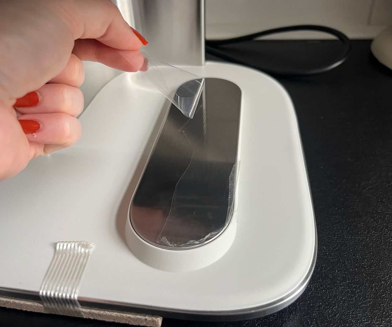 Peeling a clear plastic sticker off of a stainless steel strip on the ninja crispi dualzone air fryer, the sticker is shredding into a few pieces