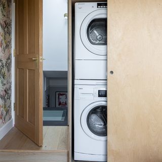 Washing machine and tumble dryer stored vertically in cupboard