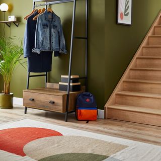hallway with stairs and a storage unti with coat hooks and a colourful runner