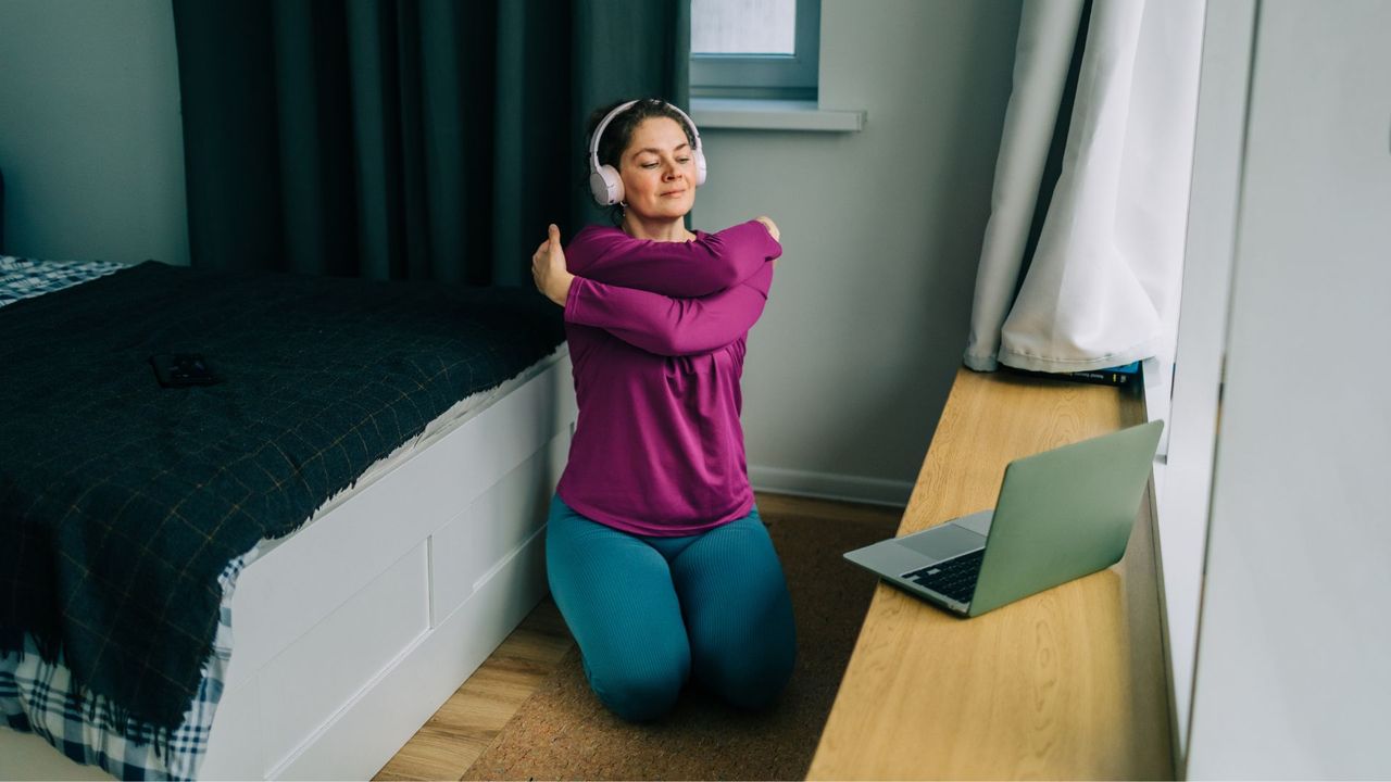 Woman sitting on yoga mat at home stretching