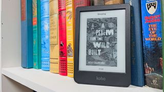 A Kobo Clara BW ereader propped up on a shelf of books