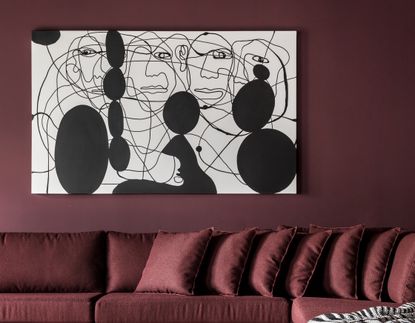 A burgundy living room with a black painting