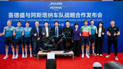 XDS Astana Team stand with their bike in a line for photographs