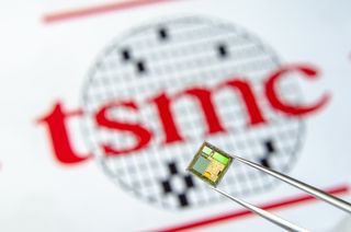 A chip being held in front of the TSMC logo.