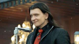 Calypso standing in front of microphone smiling in Twisted Metal Season 2 Episode 11