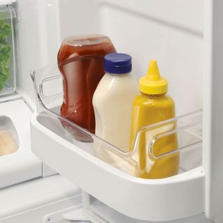 a variety of condiments in a portable caddy in a fridge door