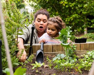 Mother showing child how to grow vegetables