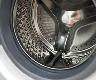 The inside of a clean silver front loading washing machine drum with grey plastic baffles