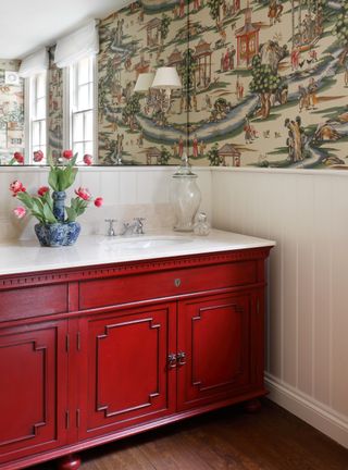 Bathroom with red vanity, wallpaper and mirror wall