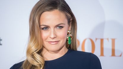 alicia silverstone in a blue top and green earrings at a press event 