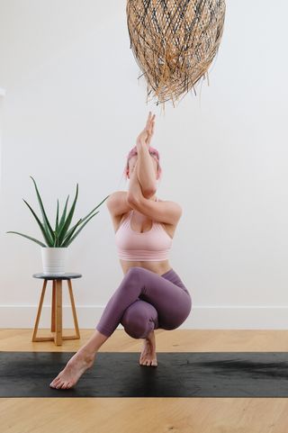 woman with pink hair practising yoga in modern space
