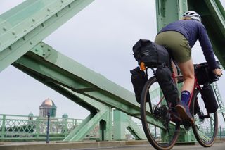 Anna cycling over a bridge into Hungary with a view of the Basilica of Esztergom