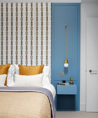 bed with upholstered headboard and blue wall panels with shelf