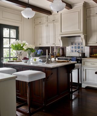 Kitchen with tile backsplash with decorative tile surrounded by white, ivory cabinets and dark wood island