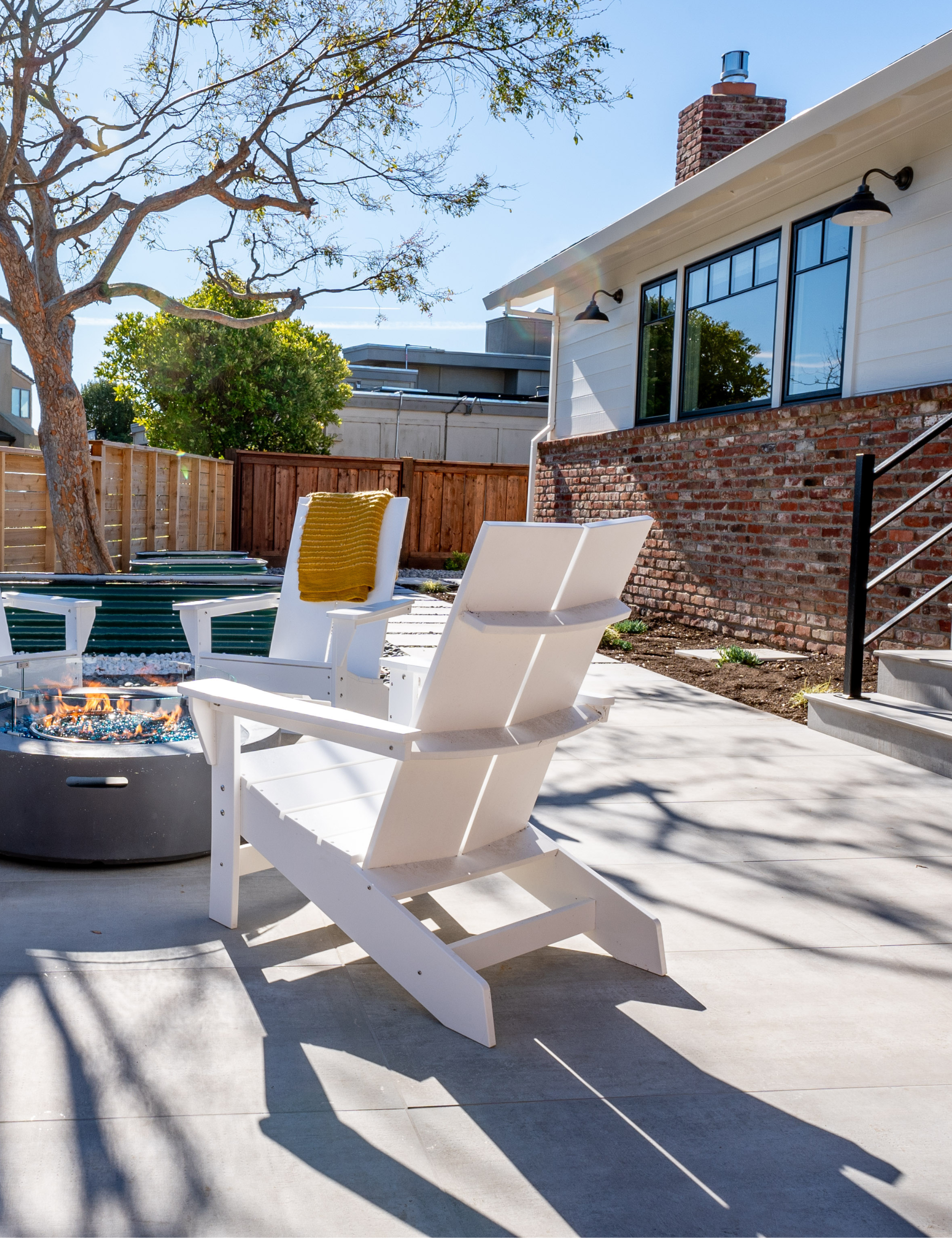 Retro Americana patio area by Studio SQUIRE styled with a trio of matte black outdoor gooseneck barn lights lining the exterior