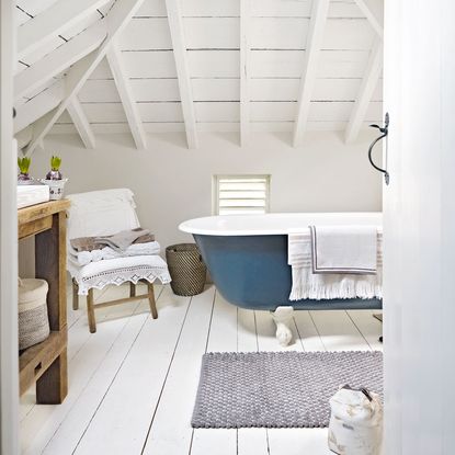 attic bathroom with wooden flooring and blue bathtub