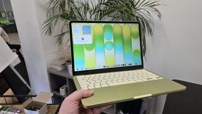 MacBook Neo laptop on a desk with plant in background