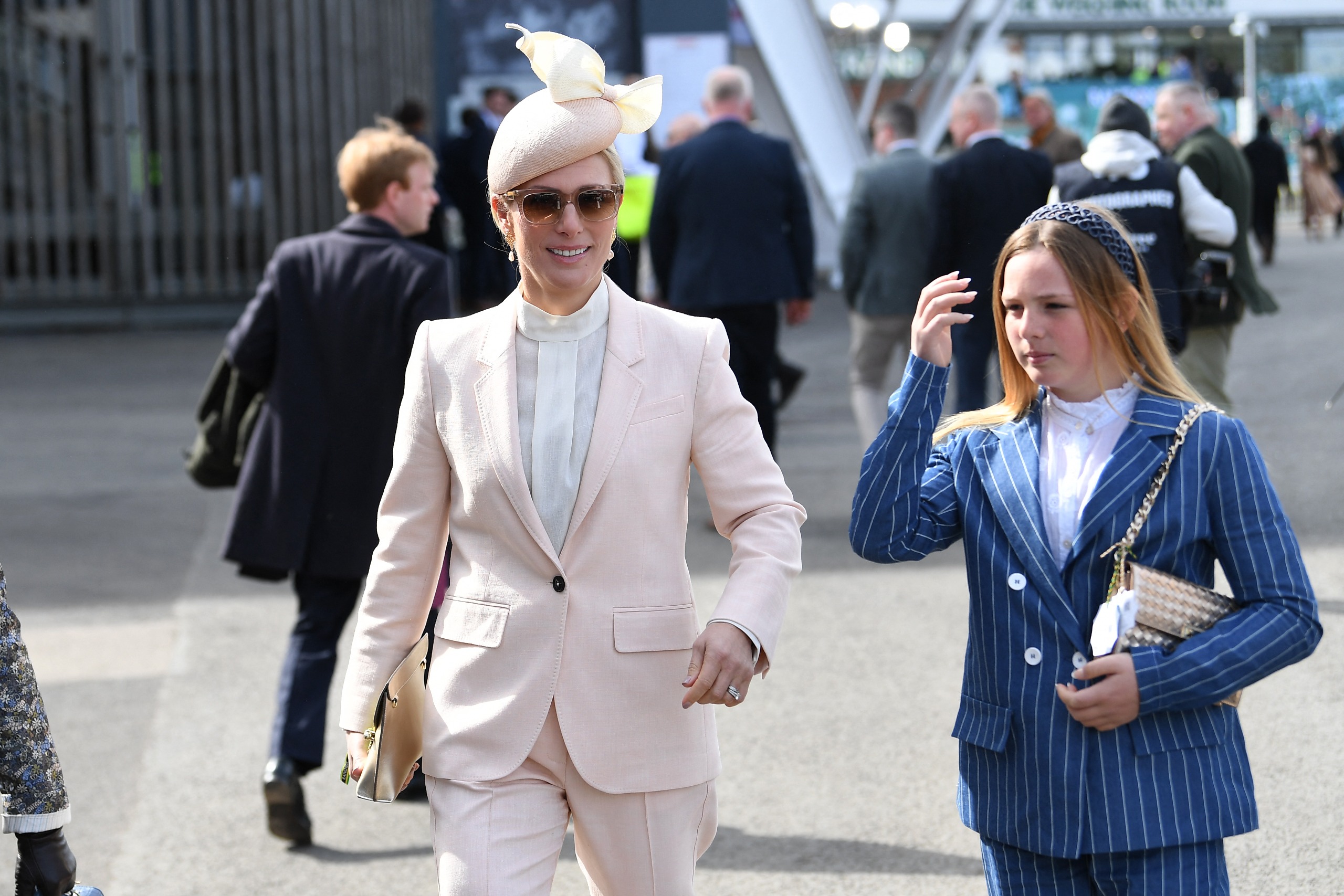 Zara Tindall wearing a pink suit walking with Mia Tindall wearing a blue striped suit