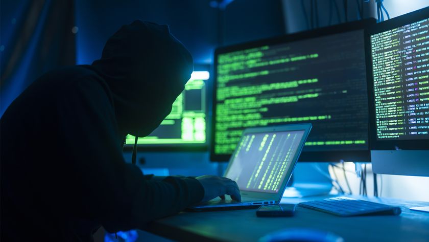 Hooded hacker with bad posture hunches over their Matrix-code workstation.