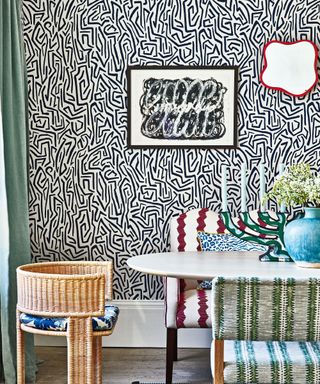 maximalist dining room with abstract, monochrome wallpaper, contrasting textured dining chairs