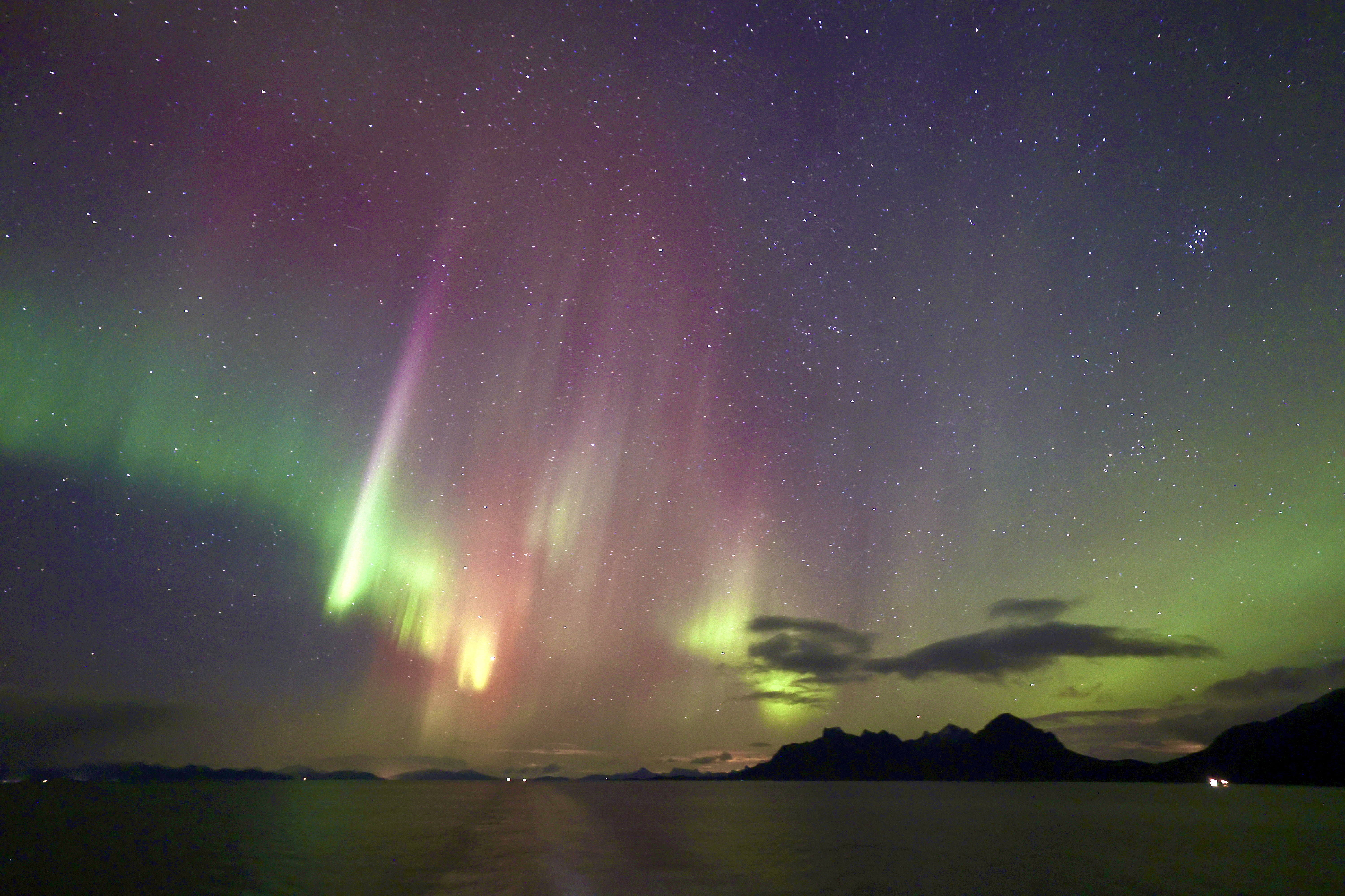 northern lights colored green, magenta and slightly yellow stretch through the sky.