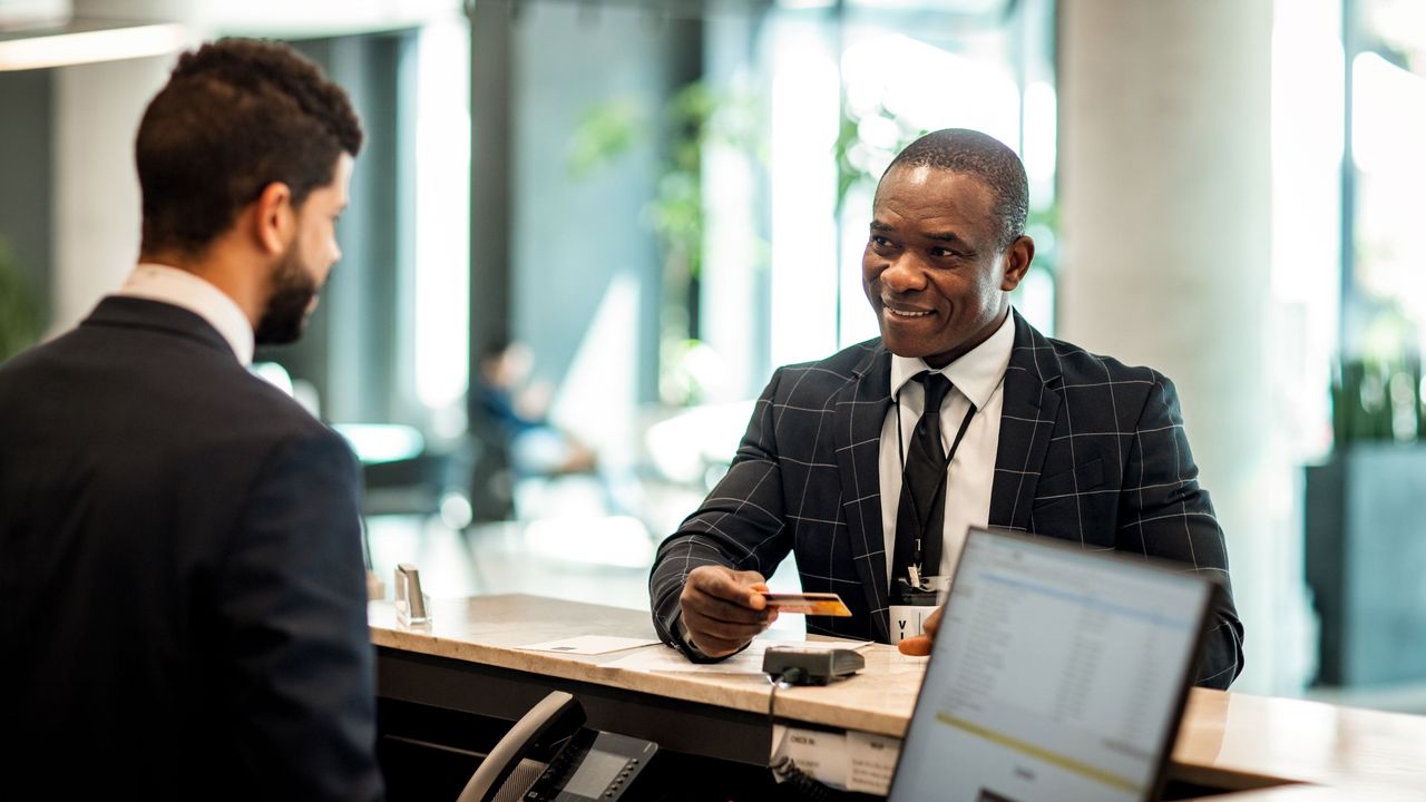 A business man pays for a hotel stay with a credit card. 