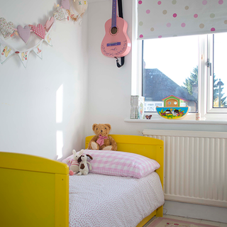 children's white bedroom with yellow bed and cushions